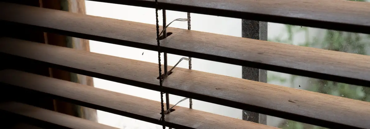 Cinta de una persiana de lamas de madera tensada junto a la ventana