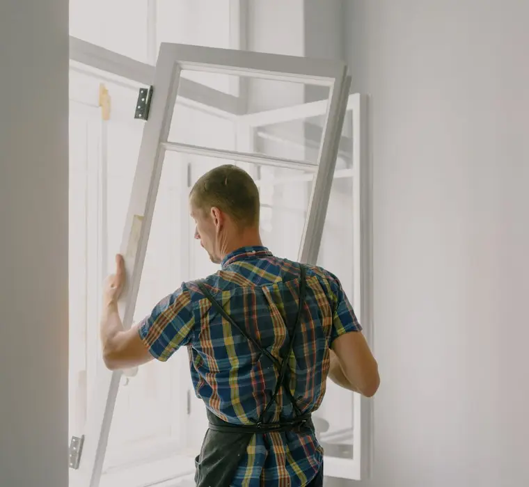 Operario sujetando el marco de una ventana en una vivienda, trabajo de persianista en Pamplona