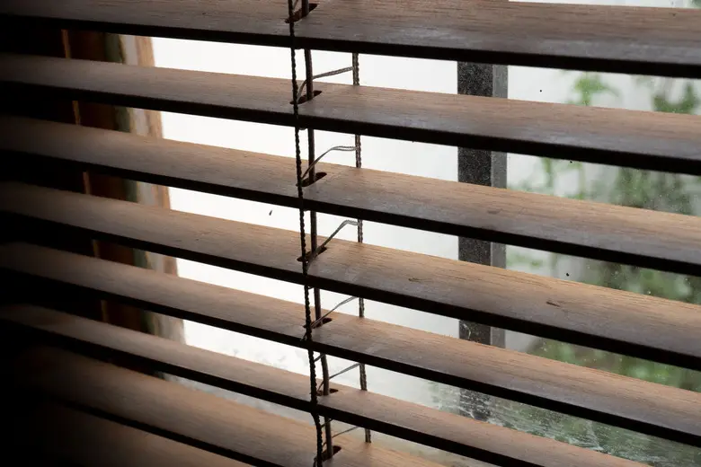 Cinta de una persiana de lamas de madera con la luz de la ventana de fondo