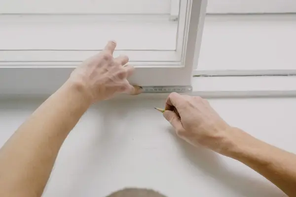Medición con metro y lápiz sobre el marco blanco de una ventana, como en una visita de persianista en Pamplona